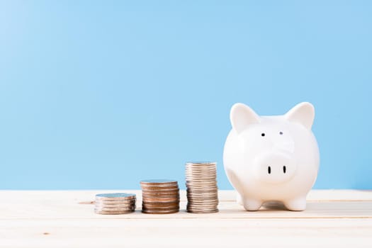 Piggy bank with stack coins isolated blue background. Saving money and investment concept.