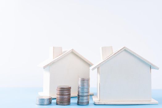 Wooden house with stack coins isolated grey background. Property investment and house mortgage financial concept.