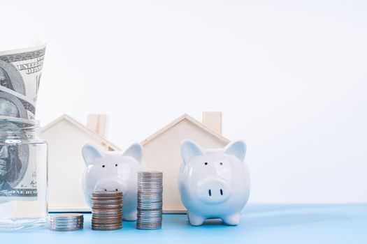 Piggy bank with wooden house and stack coins isolated grey background. Property investment and house mortgage financial concept.