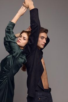 A sexy man in an unbuttoned shirt and a woman in a dress with hands raised up. High quality photo