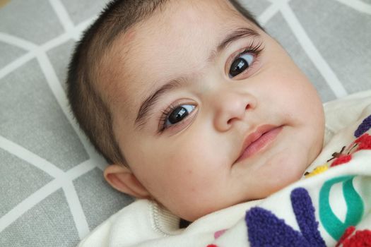 Baby girl with lovely face, big eyes and cute face gesture. Toddler baby making sweet activities