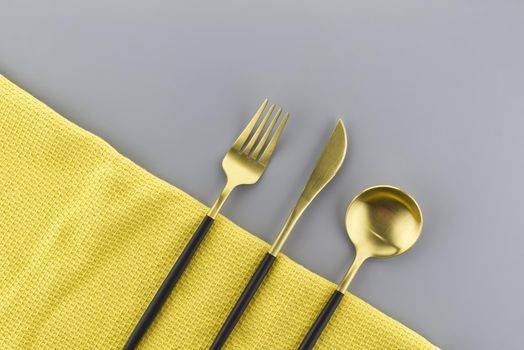 Set of stylish black and gold cutlery on a two tone grey and yellow background with copy space viewed as a flat lay. Main color trend of the year