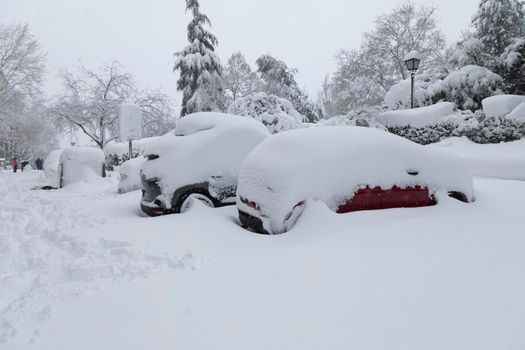 Madrid, Spain - January 09, 2021: Cars parked, blocked and completely buried by snow and ice, on a snowy day, due to the Filomena polar cold front.