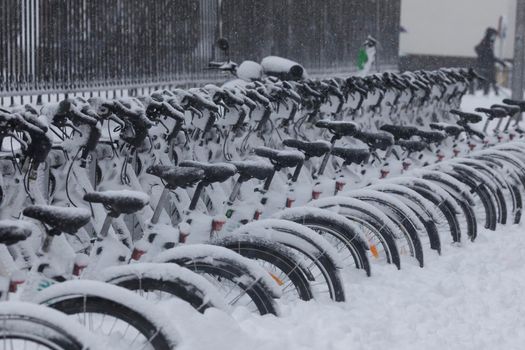 Madrid, Spain - January 09, 2021: Row of electric bicycles of the public service of the EMT company, Bicimad, buried in snow, on a snowy day, due to the Filomena polar cold front.