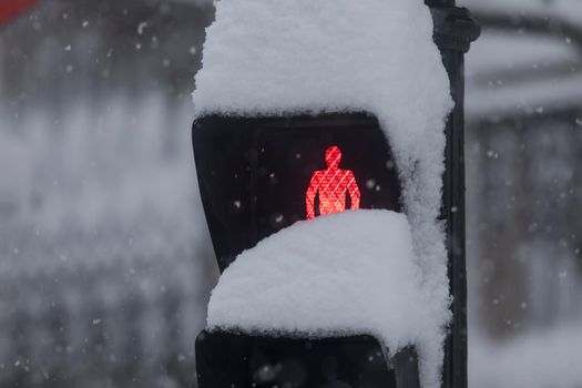 Madrid, Spain - January 09, 2021: A red traffic light, completely covered with snow, on a snowy day, due to the Filomena polar cold front.