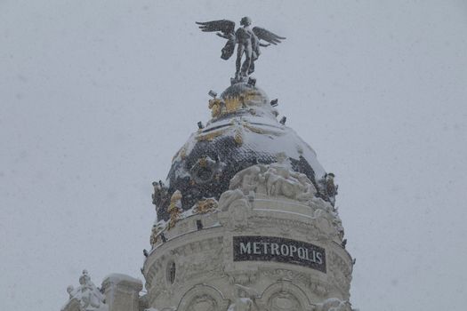 Madrid, Spain - January 09, 2021: Famous Metropolis building between Calle Alcala and Gran Via, on a snowy day, due to the Filomena polar cold front.