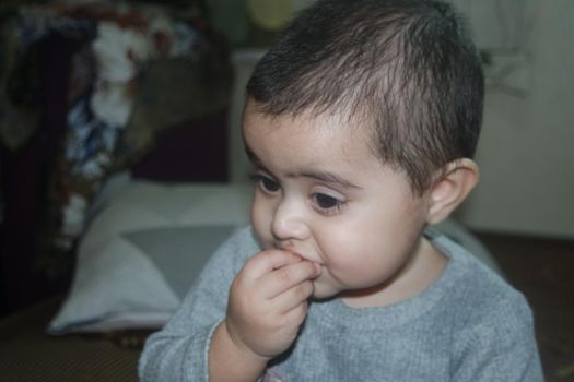 Baby girl with lovely face, big eyes and cute face gesture. Toddler baby making sweet activities