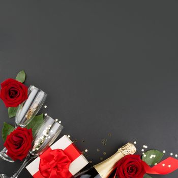 Valentines day composition flat lay top view with gift box rose flowers gift champagne and hearts design element on black background with copy space for text