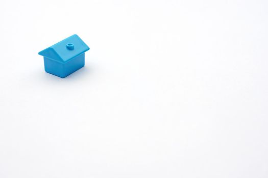 Simply minimal design one single blue toy miniature or model cottage house on white background and copy space. Purchasing or buying eco house or rental of property and constructing new small cosy home