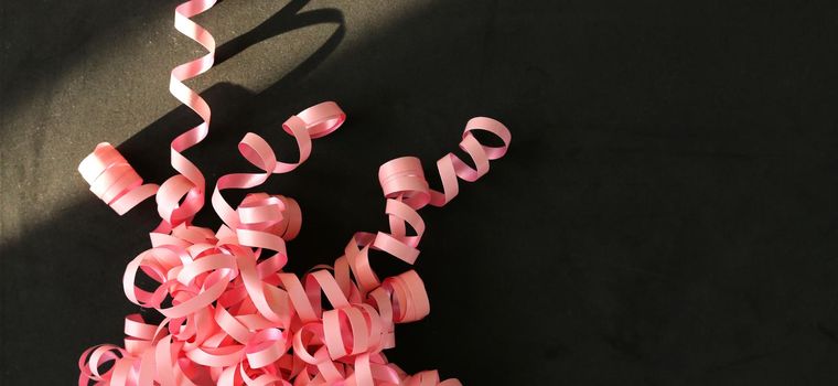 Pink serpentine streamer on black background Party accessory