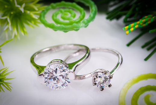 Closeup Diamond gem wedding rings  with green leaves on white background