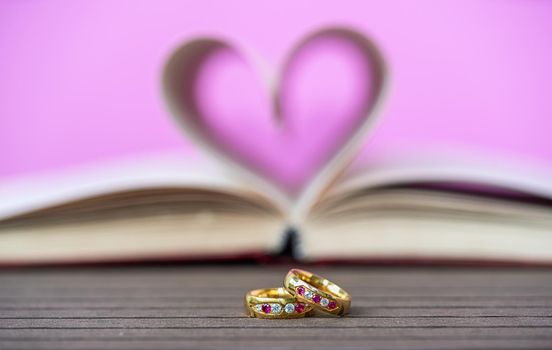 Pages of book curved into a heart shape and wedding ring . Love concept of heart shape from book pages