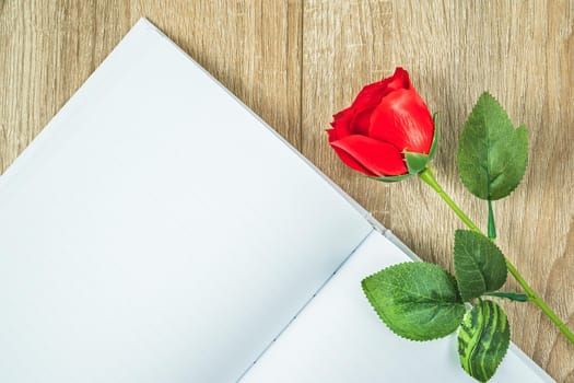 Top view shot of  empty blank notebook diary and red roses on wood table,Valentine concept