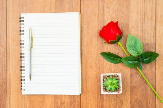 Top view Red roses on wooden table and pen on notepad on wood deck ,Valentines day concept