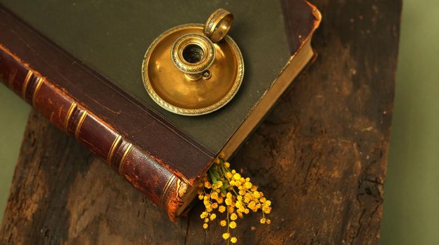 Old antique book with candlestick candle holder on old wood background. Memory, past, family album concept