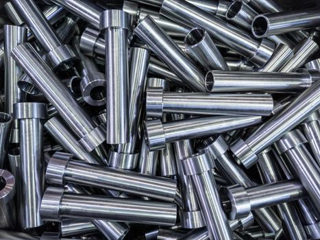 full frame abstract indistrial background of pile of shiny steel tubes after cnc turning operations
