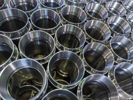 dark industrial background with cnc machined shiny silver colored steel pipes - selective focus and lens blur technique