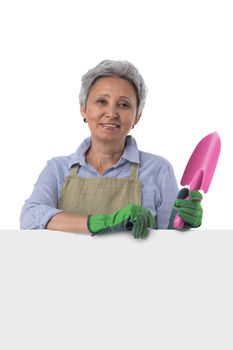 Mature asian woman gardener with scoop standing behind blank banner with empty copy space for text isolated on white background