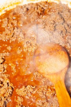 Ground angus beef stirfried in a pan with a wooden spoon