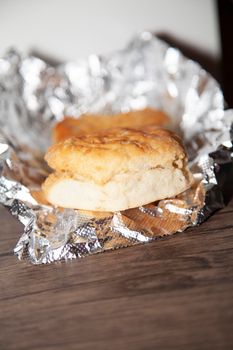 Two buttermilk biscuits on foil on a wooden table