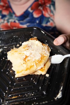 Partially eaten plain pancakes with butter and light syrup