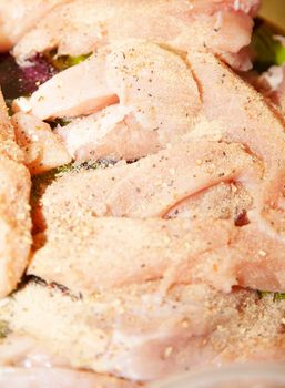 Raw chicken strips topped with lemon pepper seasoning