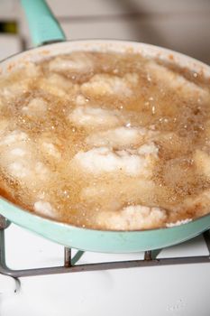 Close up of breaded chicken strips frying in a pan