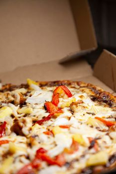 Barbeque chicken, red bell pepper, onion, pineapple pizza in its carryout box