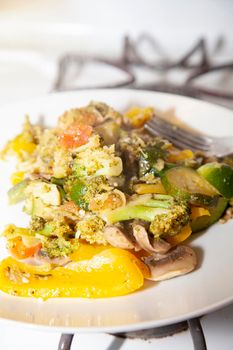 Zucchini, broccoli, yellow bell pepper, tomato, and mushroom stir-fry on a white plate