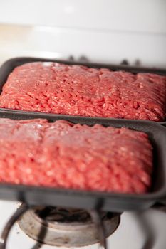 Two open packages of ground angus beef on a stove