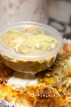 Guacamole on a carry out tin of nachos with cheese, chips, jalapenos, and sour cream