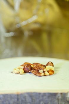 Peanuts, Brazil nuts, pecans, cashews, and almonds on a wooden slab in a yellow hue