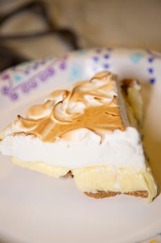 A single slice of lemon meringue pie on a paper plate