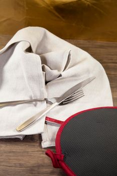 Fork and knife on a grey napkin, next to a red and black potholder