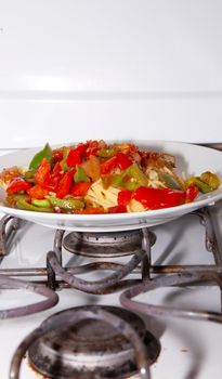 Red and green bell peppers on cooked spaghetti