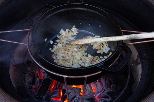 Making onions in a dutch oven on a barbecue with fire beneath