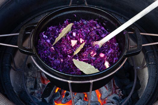 Making red cabbage in a dutch oven on a barbecue with fire beneath