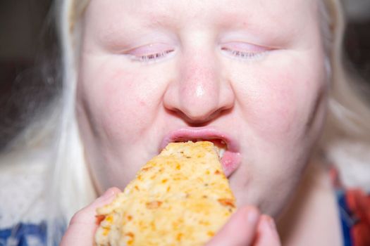 Albino woman eating a bacon and cheese scone