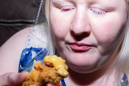 Woman staring at a partially eaten chicken tender, considering whether she wants to continue eating