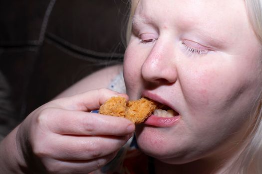 Obese woman eating a chicken tender