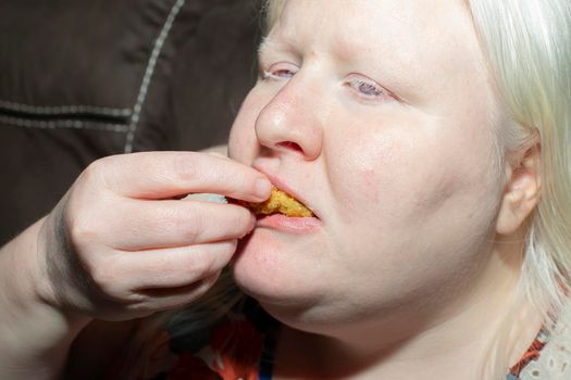Obese, albino woman enjoying eating fried pickle slices
