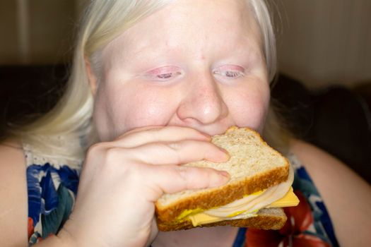 Woman eating a lopsided chicken and cheese sandwich
