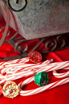 Candy canes on a red, Christmas background with a tin sleigh and Christmas Reese's peanutbutter cups in the background