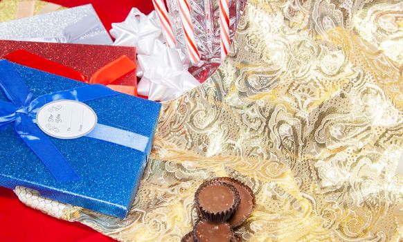 Chocolate candies, candy canes, and red and blue presents next to a gold stocking