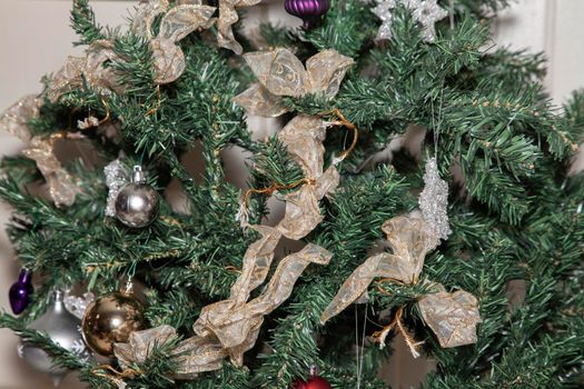 Purple, silver, and gold globes and gold and white ribbon on an artificial Christmas tree