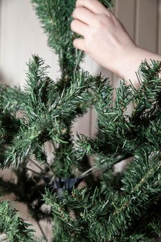 Woman shaping the limbs of an artificial green Christmas tree