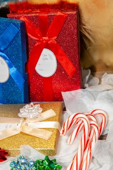 Gold, blue, and red gift boxes near red, blue, and green bows and candy canes