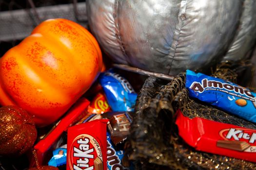 LOUISIANA/USA – OCTOBER 31 2019: Silver pumpkin, orange pumpkin, small sequined pumpkins, black and gold mesh decoration, with Reese's, Kit Kat, and Almond Joy candies to hand out.