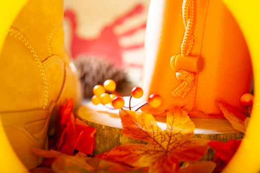 Hunter orange pouch on a wooden slab next to orange and red berries and leaves and a boot with a pinecone and a red hand turkey in the background