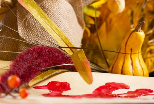 Red hand turkey on vanilla construction paper and orange berries and red and yellow foliage next to burlap and a yellow squash